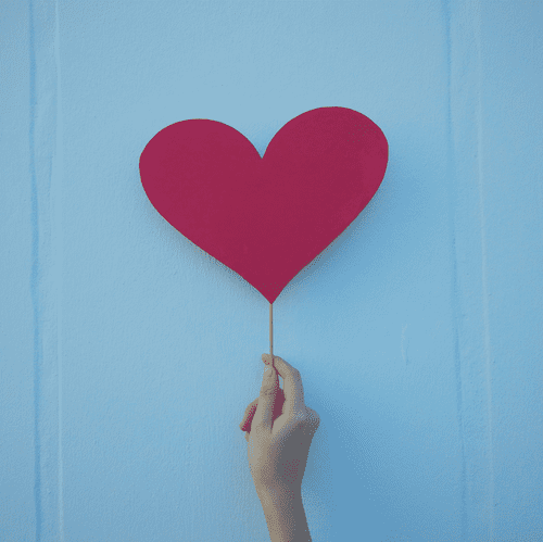 Das Bild zeigt eine Hand, die ein rotes Herz vor einer blauen Wand hält, und symbolisiert die Voraussetzungen für eine Paartherapie in Berlin. Es steht für Liebe, Unterstützung und die Bereitschaft, an der Beziehung zu arbeiten, was essenziell für eine erfolgreiche Paartherapie ist. 